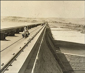 Old picture of a man on a donkey with the Aswan dam being built