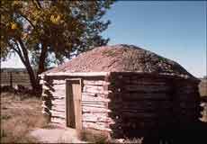 Hogan made of logs, with a wooden door and packed-earth roof